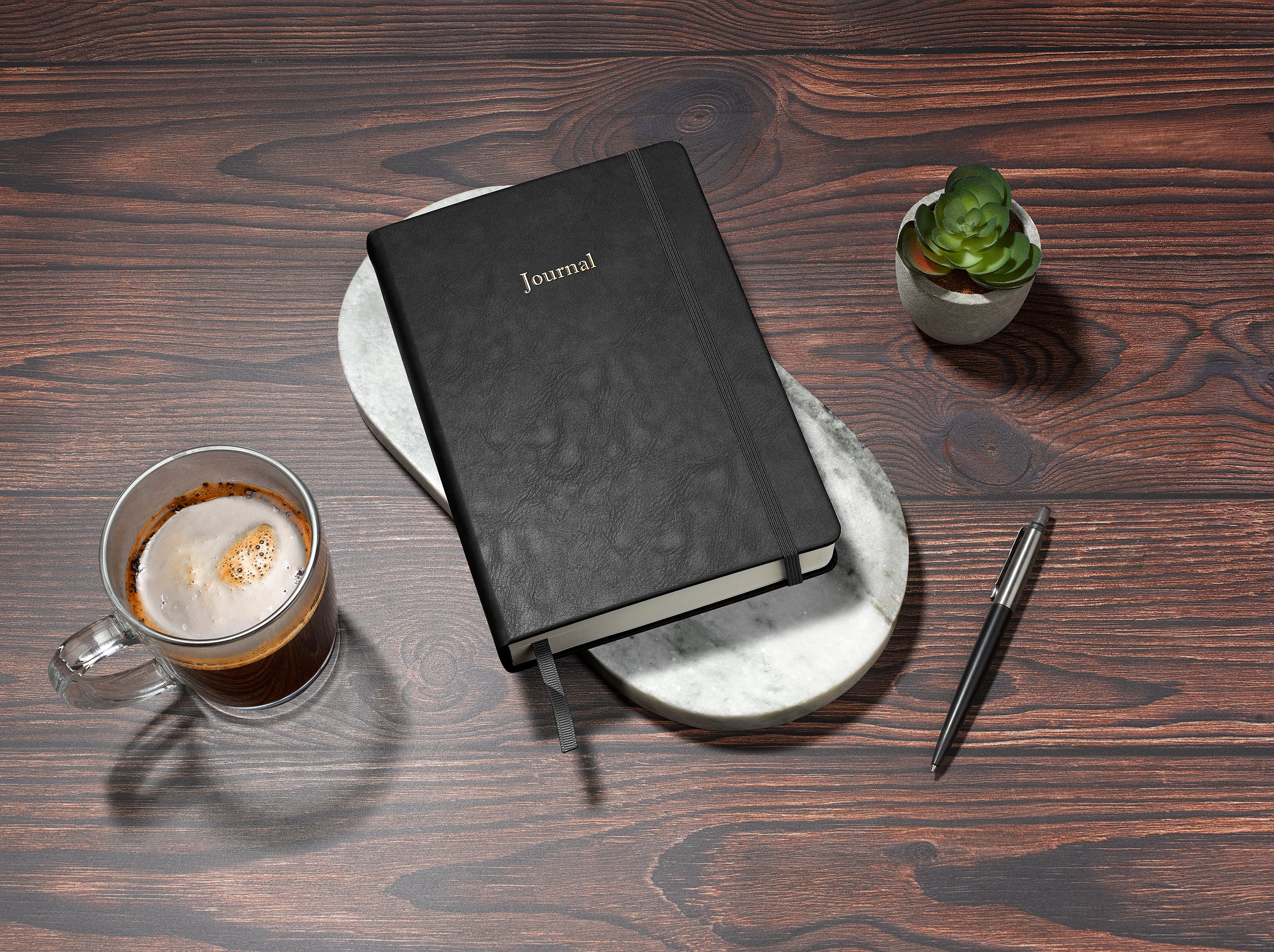 black financial planner and budgeting book in a5 on a desk with a coffee and plant