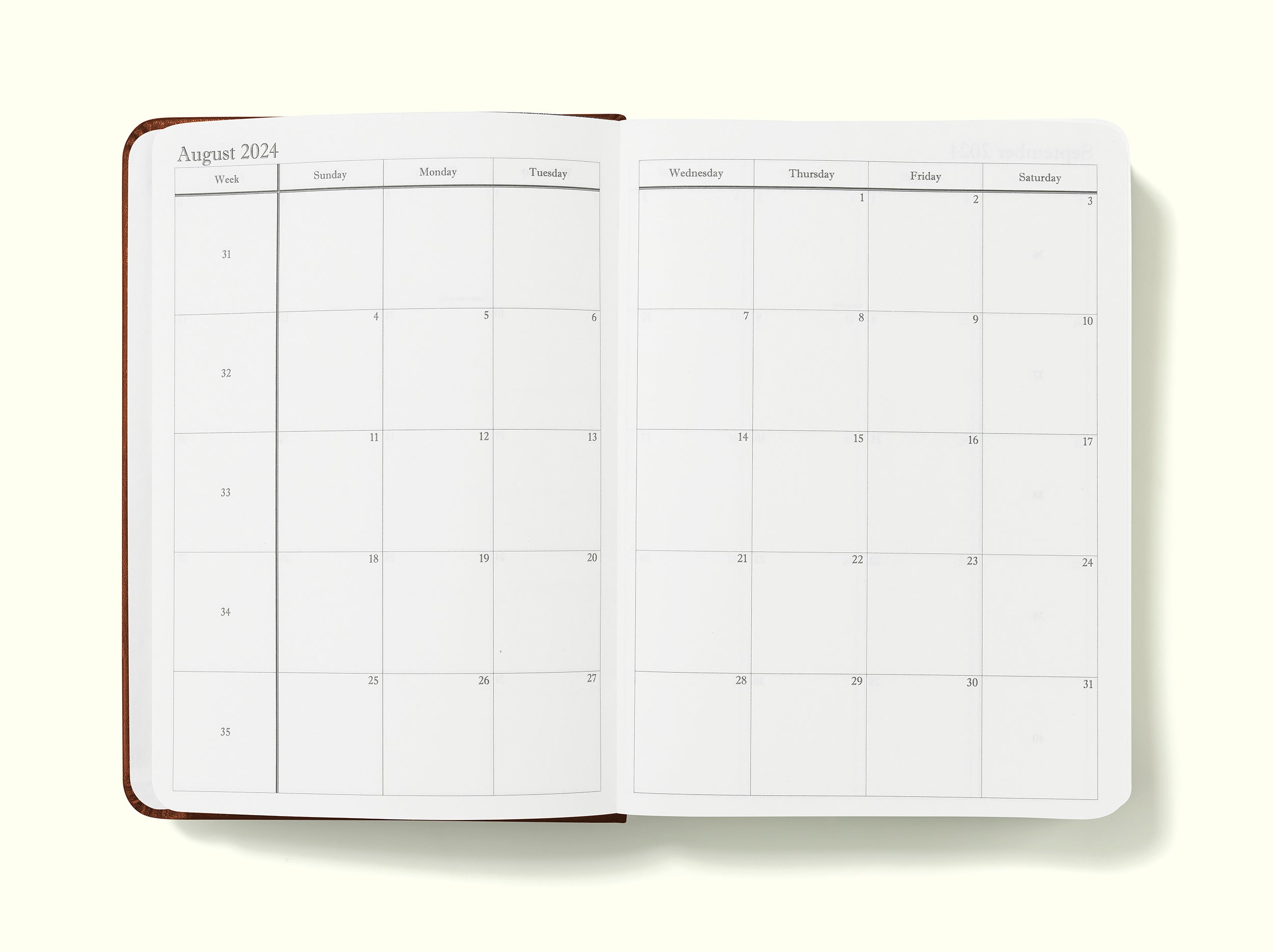 monthly planning pages of brown 2024 daily journal in a6 sitting on blank background