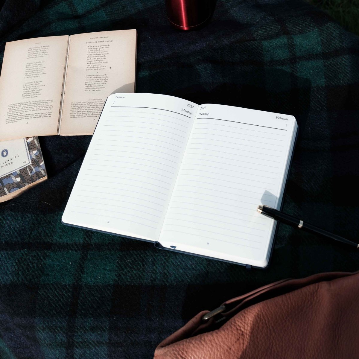 Open dark executive journal with ruled pages and pen, ready to write