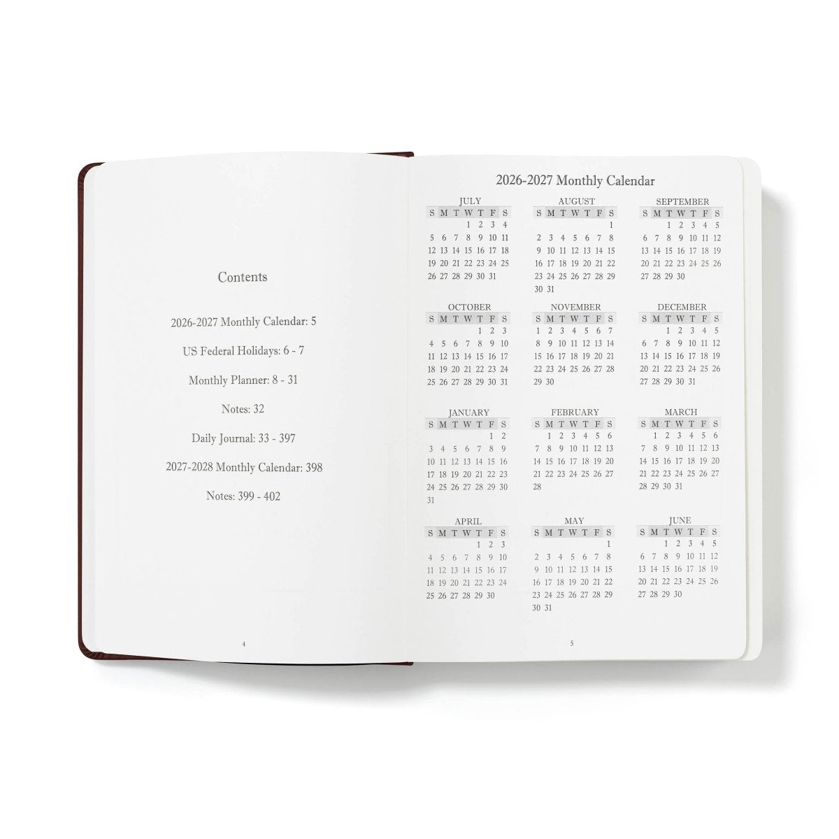 Mid-year planner open to monthly calendar overview, white paper with brown binding
