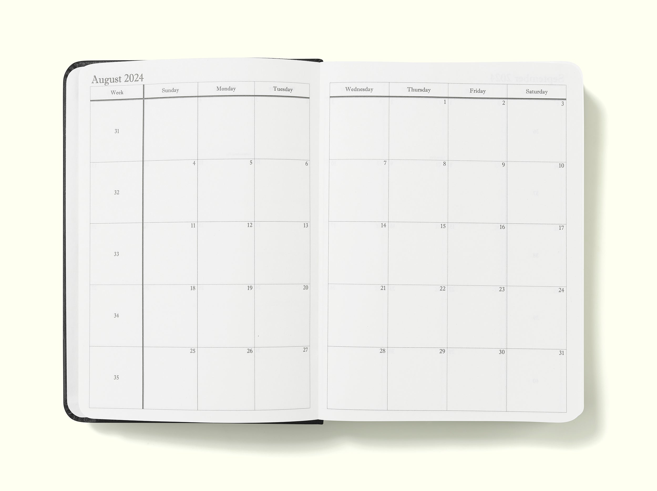 monthly planning pages of black 2024 daily journal in a6 sitting on blank background