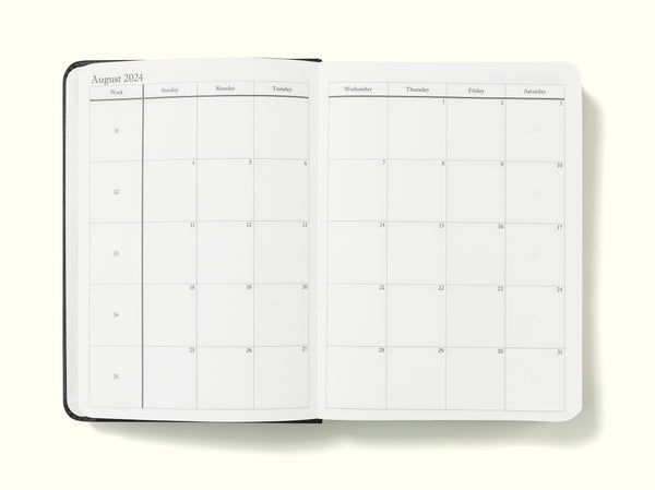 monthly planning pages of black 2024 daily journal in a6 sitting on blank background