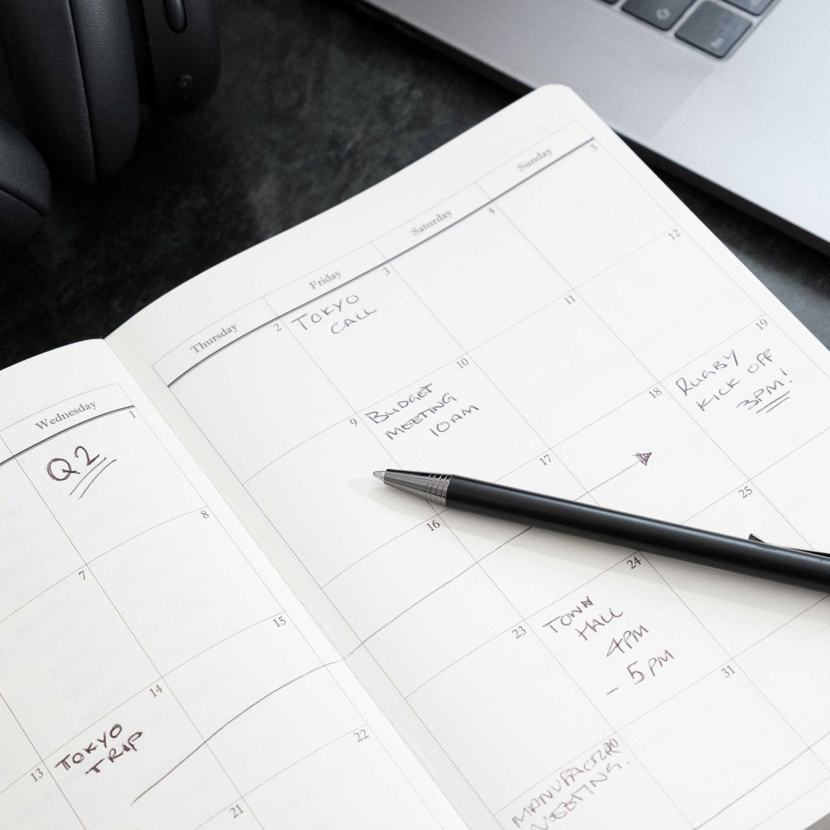 Open executive journal planner pages with handwritten notes and a black pen