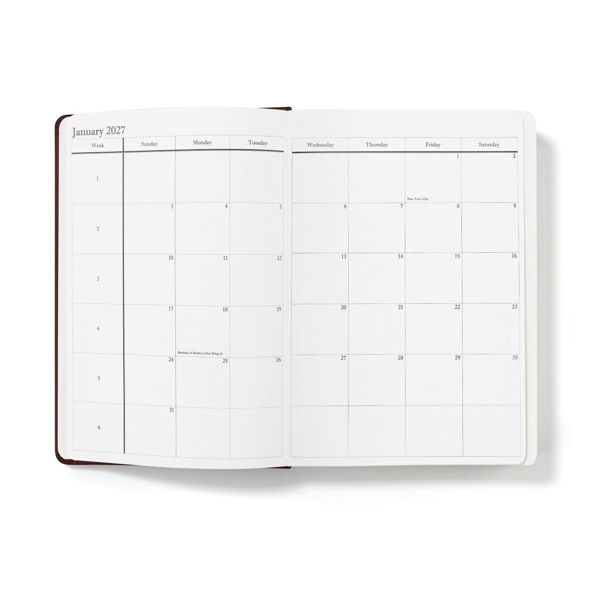 Mid-year planner open to January 2027 calendar grid, white pages with brown spine