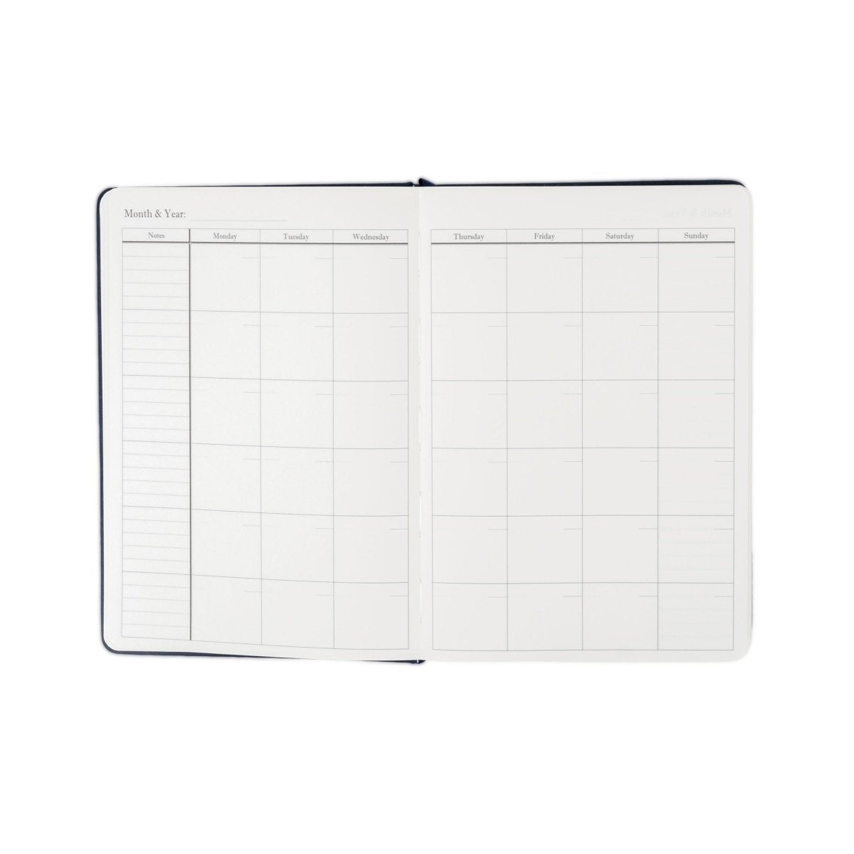 Undated planner journal opened to monthly and weekly grid pages, dark blue cover.
